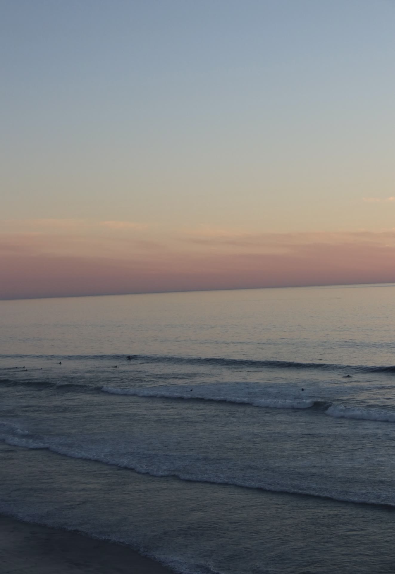 Surfers in the lineup at a glassy dusk session