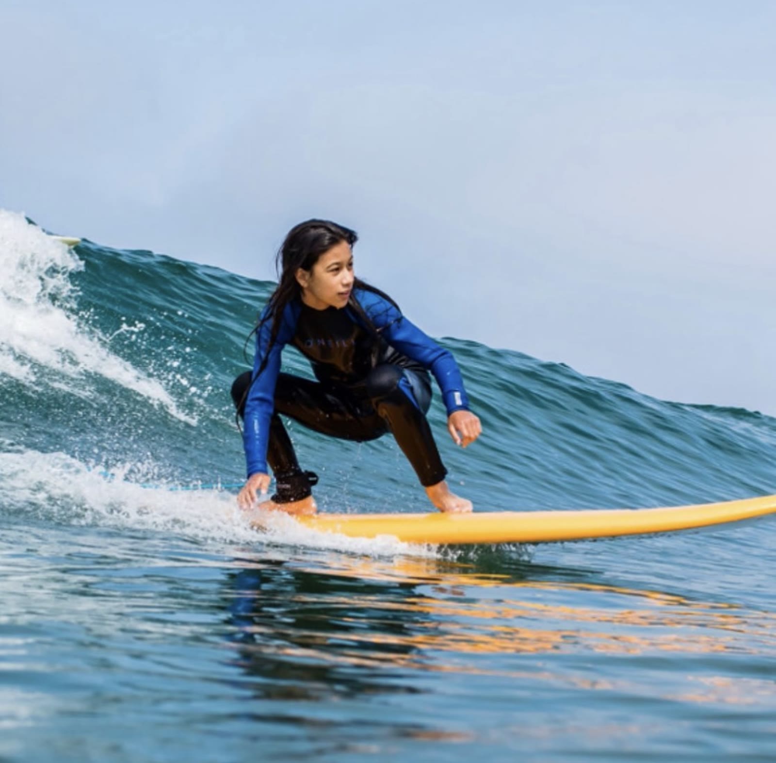 Young surfer riding a wave on a soft-top board